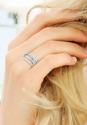 Bague en argent avec trois bandes entrelacées, ornée de petites pierres précieuses transparentes, présentant une finition lisse et une texture polie.