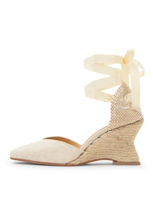 Beige sleehak espadrille met gesloten puntige neus, geweven textuur hak en lange crèmekleurige lint die om de enkel wordt gewikkeld.