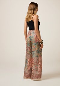 Pantaloni a gamba larga con un motivo floreale multicolore. Realizzati in tessuto leggero, presentano una vita alta e dettagli eleganti all'orlo.
