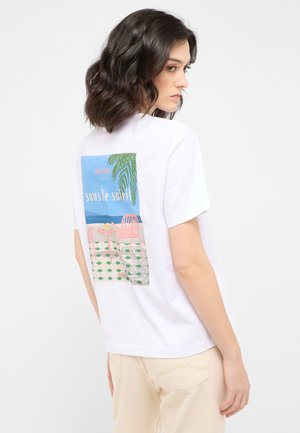 Weißes T-Shirt mit kurzen Ärmeln, das auf der Rückseite einen bunten Grafikdruck mit Palmenblättern, pinken Stühlen und Strandlandschaft zeigt.