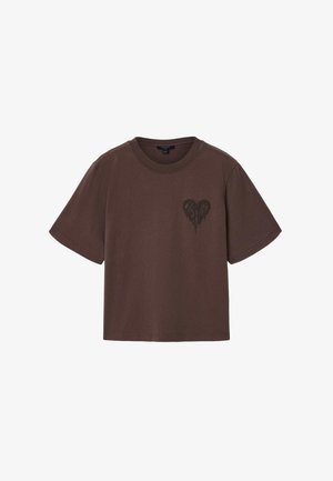T-shirt marron à manches courtes, courte, avec un col rond et un petit motif en forme de cœur foncé sur le côté gauche de la poitrine.