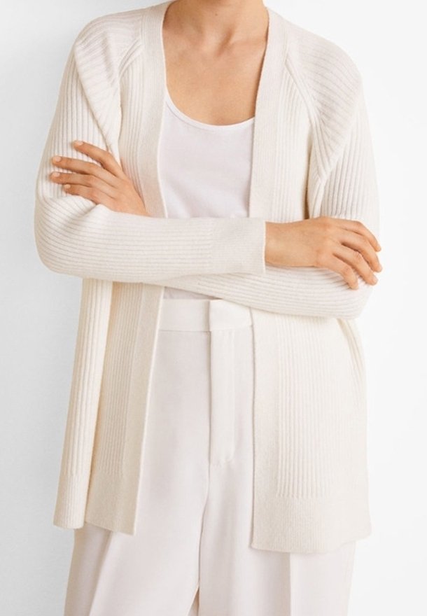 Ivore geribde cardigan met een open voorkant, lange mouwen en een gestructureerde stof. Draagt over een witte tanktop en lichte broek.