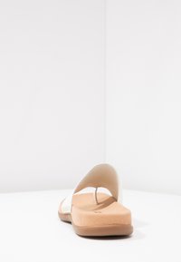 White slip-on sandal with a smooth upper, tan cushioned insole, and a rubber outsole. Simple design with a split toe detail.
