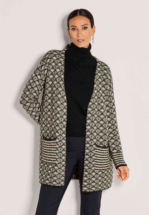 Gebreide cardigan in crème en zwart, met een geometrisch patroon, open voorkant, twee voorzakken en contrasterende gestreepte accenten op de zakken.