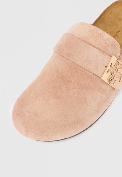 Roza semišova lahko obutev s zaobljenim nosom, ki ima dekorativni zlati kovinski trak s sponko čez zgornji del. Ravna podplat in mehak otip.