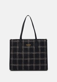 Sac cabas en tweed noir à motif à carreaux, avec des anses noires et des accents de logo dorés. Forme carrée avec une finition texturée.