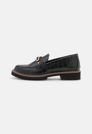 Sorte læder loafers med et krokodillemønster, en guldfarvet hardwaredetalje og en gummisål med synlig mønstring.