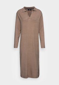 Robe tricotée brun clair, longueur genou, avec un col en V, des manches longues et des fentes sur les côtés. Texture douce et détail de ourlet côtelé.