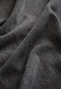 Tejido gris texturizado con un patrón tejido, que presenta pliegues drapeados que exhiben su superficie suave y lisa, y un brillo sutil.