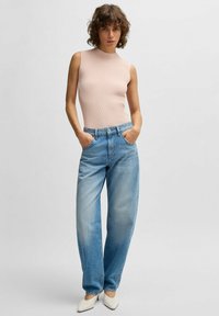 Vaaleanpunainen ribbineuleinen ilman hihoja oleva toppi, joka on yhdistetty vaaleansinisiin korkeavyötäröisiin leveälahkeisiin farkkuihin ja valkoisiin kärkikengiin.