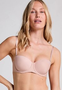 Ljusrosa bh med bygel, slätt tyg, justerbara band, sömlösa kupor och mittsöm för extra stöd.