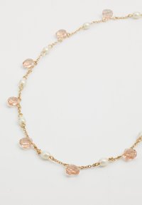 Colar de corrente dourada com pedras texturizadas em rosa claro e pérolas brancas, alternando em um padrão delicado.
