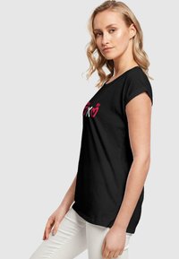 Svart kortermet bomull t-skjorte med fargerik "XOXO" tekstdesign foran, med en avslappet passform og rund hals.