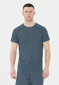 Tummanharmaa urheilupaita, jossa on lyhyet hihat, kevyt kangas, saumaton muotoilu ja teksturoitu pinta. Sopii aktiiviseen pukeutumiseen.