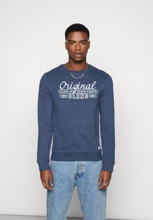 Marineblå sweatshirt med ribbede manchetter og kant, med hvid tekst der siger "Original Claim Your Denim Rights Blend" på brystet.