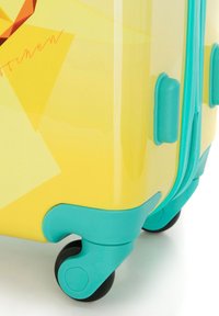 Valise rigide avec une surface jaune brillant, des accents turquoise et des roues noires. Présente des motifs géométriques et une fermeture éclair robuste.