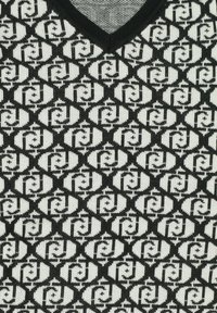Maglione a maglia bianco e nero con scollo a V, caratterizzato da un design geometrico di forme e texture intrecciate.