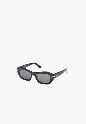 Black rectangular sunglasses with gray lenses, featuring gold accents on the temples and a matte finish. Angular design with wide frames.