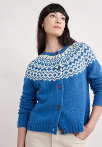 Siniset neulotut neuletakit, joissa on valkoinen kuvioitu kaulus, pyöreä pääntie, nappikiinnitys sekä joustinneuleet hihoissa ja helmassa.