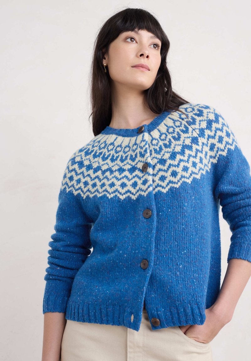 Siniset neulotut neuletakit, joissa on valkoinen kuvioitu kaulus, pyöreä pääntie, nappikiinnitys sekä joustinneuleet hihoissa ja helmassa.