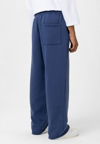 Marineblauwe sweatpants met een elastische tailleband, zijzakken en een achterzak. Gemaakt van zachte stof met een ontspannen, wijde pasvorm.