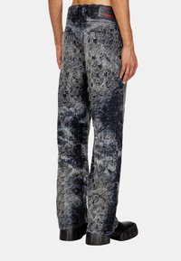 Pantalons en denim avec un design texturé et froissé dans des nuances de bleu et de gris. Présentent un motif de couture clair et des poches arrière, avec une coupe décontractée.