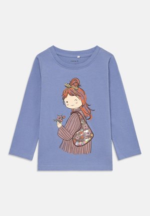 Camicia a maniche lunghe blu con una grafica di una ragazza dai capelli castani, che tiene dei fiori e una borsa con motivo, realizzata in morbido cotone.