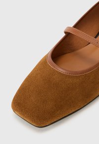 Flats Mary Jane en suède marron avec un bout carré, dotées d'une fine sangle en cuir et d'une doublure intérieure lisse.