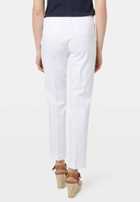 Witte op maat gemaakte broek met een rechte pijp, gemaakt van lichtgewicht stof, met twee achterzakken en een nette afwerking aan de zoom.