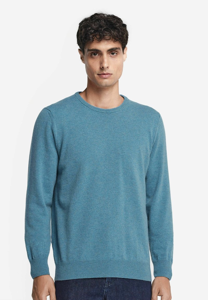 Ljusblått crew-neck tröja gjord av mjukt stickat material. Har långa ärmar, ribbade manschetter och en rak nederkant med en strukturerad yta.