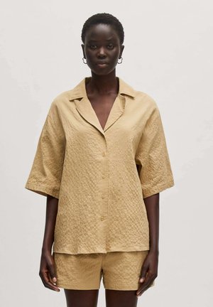 Beige, strukturiertes Hemd mit kurzen Ärmeln, Knopfleiste und breitem Kragen, kombiniert mit passenden Shorts. Glattes, gewebtes Material.
