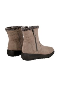 Par de botas de invierno de ante beige con suelas de goma negra y cremalleras laterales, con forro de piel de peluche en el tobillo.