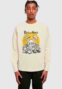 Cremfarbener Sweatshirt mit einem grafischen Design aus "Rick and Morty", das einen gelben Kreis, komplexe Illustrationen und schwarze Akzente aufweist.