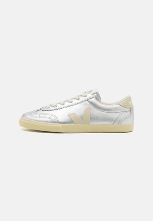 Sneaker in pelle argento con accenti beige, punta rotonda, superficie testurizzata e lacci piatti. Logo prominente sul tallone e sul lato. Suola in gomma.
