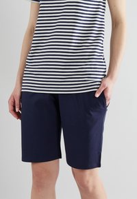 Pantalones cortos de algodón azul marino con bolsillos laterales, combinados con una camiseta de rayas azul marino y blanca, de manga corta y ajuste relajado.