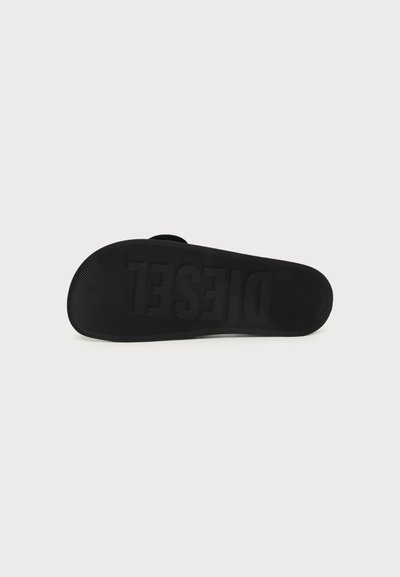 Semelle de sandale noire avec une surface texturée antidérapante et le nom de la marque "DIESEL" embossé sur le dessous.