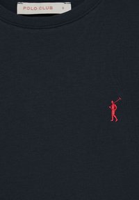 Camiseta de manga corta en color navy, hecha de algodón. Presenta una pequeña figura bordada en rojo con un palo de golf en el lado izquierdo del pecho. Textura suave y uniforme.