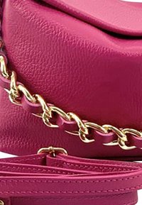 Rosa Lederhandtasche mit glatter Textur, ausgestattet mit einem goldenen Kettenriemen und einem flachen oberen Klappdeckel. Akzente beinhalten einen passenden rosa Riemen.