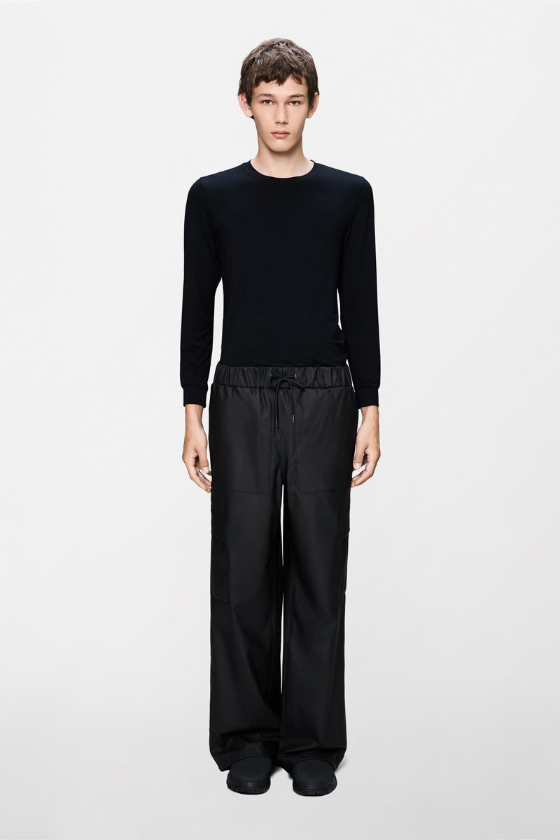 Μαύρο μπλουζάκι με μακριά μανίκια και άνετο μαύρο παντελόνι cargo με ελαστική μέση, που διαθέτει πλαϊνές τσέπες και λεία, ματ υφή.