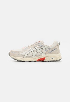 Beigefarbener und grauer ASICS Gel-Venture 6 Laufschuh mit Mesh- und synthetischem Obermaterial, gedämpfter Sohle und rotem Akzent an der Zwischensohle.