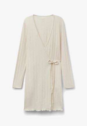 Vestido cruzado de punto de canalé en color crema con mangas largas, escote en V, cierre lateral con lazo y borde con diseño de ondas.