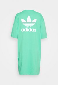 Mint green oversized t-shirt with short sleeves, featuring a large white Adidas logo and three stripes symbol on the back. Cotton material.