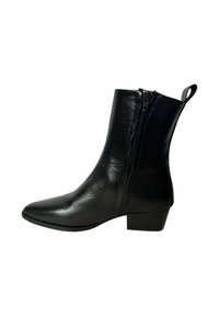 Bota de tobillo de cuero negro con punta puntiaguda, cierre lateral con cremallera y tacón bajo tipo bloque. Presenta una textura lisa y una lengüeta para tirar.