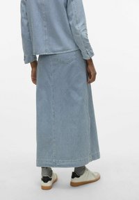 Denim krilo v svetlo modri barvi z navpičnimi belimi črtami. Ima ravno krojenje, zadnja žepa in rob, ki pada pod gleženj.