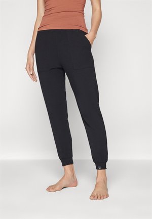 Black joggers with a relaxed fit, featuring side pockets and elastic cuffs. Made of soft fabric, they have a minimalistic design.