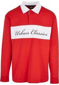 Polo roșu cu mâneci lungi, cu o dungă orizontală albă, pe care este scris "Urban Classics" cu litere negre elegante. Material din bumbac, guler ascuțit.
