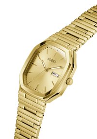 Montre octogonale dorée avec un bracelet en métal, cadran analogique, fenêtre de date et marqueurs d'heure minimalistes. Logo positionné sur le cadran.