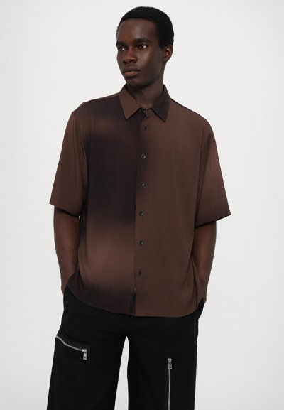 Rövid ujjú, gombos ing, amely fokozatos barna árnyalatokban készült, klasszikus gallérral és elülső gombokkal. Simaca textúra, enyhén laza fazon.