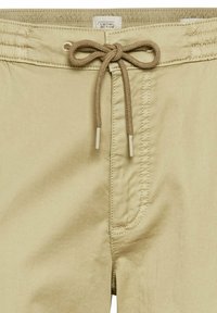 Short décontracté beige avec surpiqûres à l'avant, taille à cordon noué, et étiquette de marque Camel Active sur la ceinture intérieure.