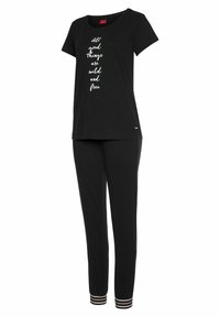 Schwarzes Baumwoll-Loungewear-Set mit einem kurzärmligen Oberteil mit weißen Text und schwarzen Hosen mit gestreiften Akzenten an den Bündchen.